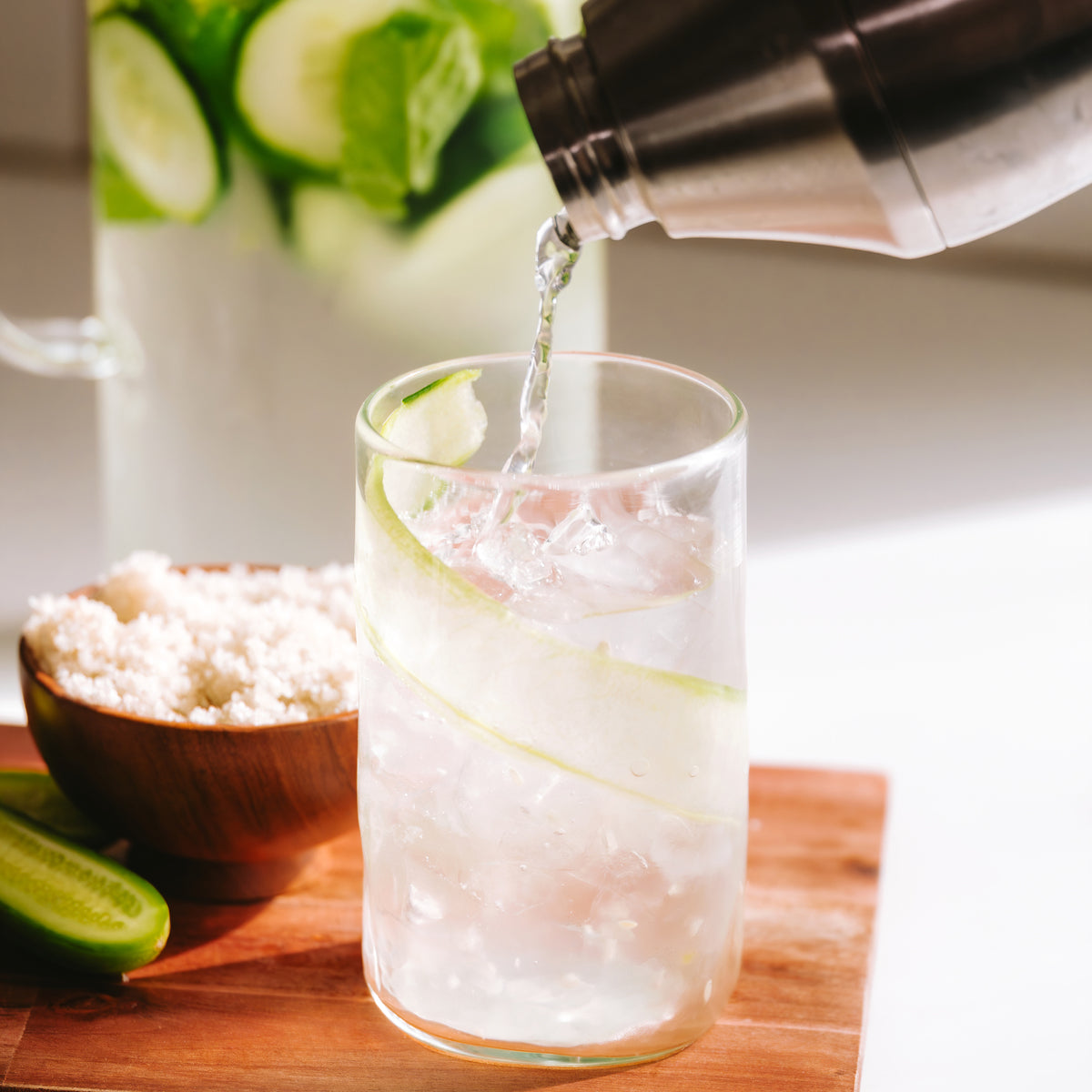 Pouring water into glass with cucumbers and a sprinkle of Celtic Sea Salt for hydration